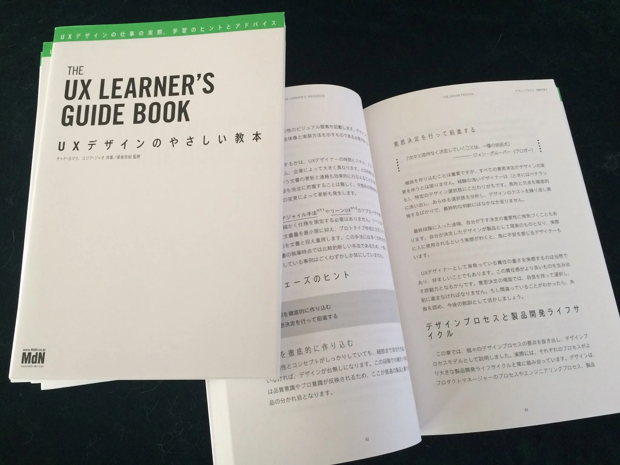 The Japanese edition of The UX Learner's Guidebook, titled UXデザインのやさしい教本 and published by MdN, lying beside an open copy showing a spread of Japanese text.